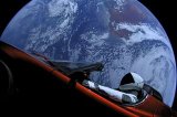 SpaceX’s Starman mannequin sits inside Elon Musk’s red Tesla Roadster with Earth in the background.